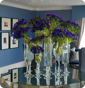 Høye vaser med lilla blomster på et speilbord
